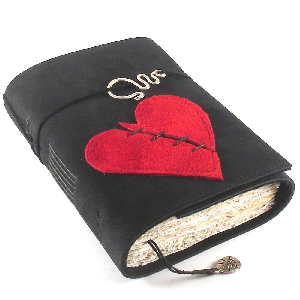 Image of a black leather-bound book with a red heart on the front. The heart has a diagonal line of black stitching across it. Image courtesy of kreativlink on DeviantArt.